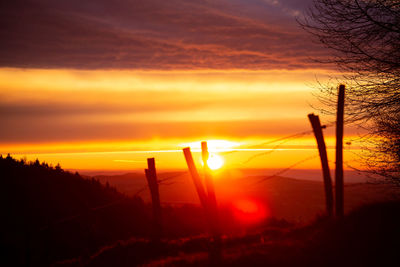 Silhouette landscape against orange sky