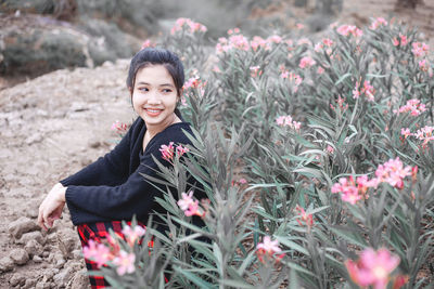 Portrait of smiling young woman sitting on plant