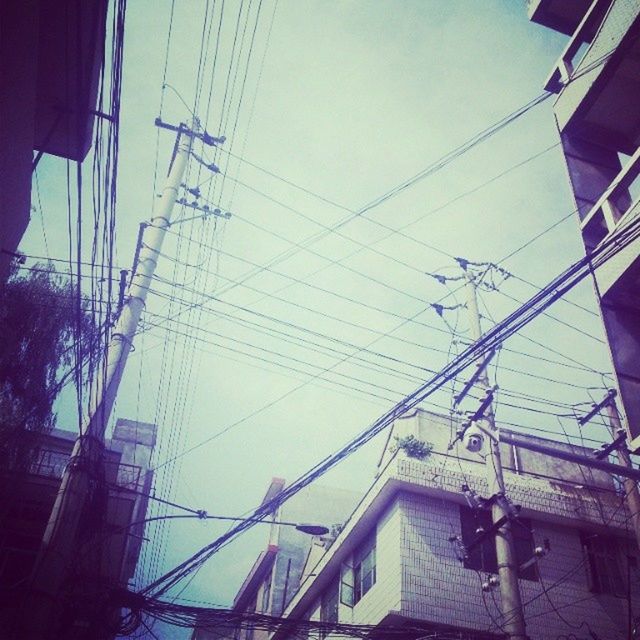 power line, building exterior, electricity pylon, built structure, electricity, low angle view, cable, architecture, power supply, connection, technology, sky, fuel and power generation, power cable, city, day, building, outdoors, sunlight, residential structure