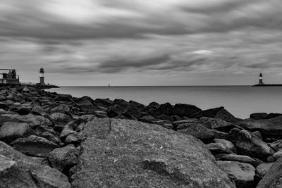 Rocks on shore by sea against sky