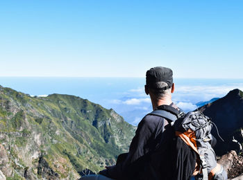 Backpacker looking at mountains against sky