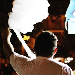 Rear view of man holding cotton candy in cafe