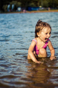 Happy girl crouching in sea shore