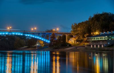 Illuminated bridge over river against sky at night