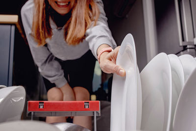 Unrecognizable woman removing plate view from inside the dishwasher