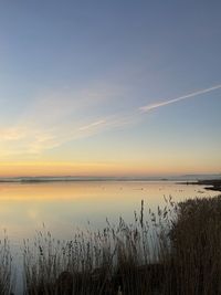 Scenic view of lake against sky at sunset