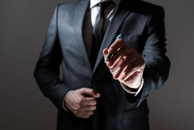 Midsection of businessman holding trophy against black background