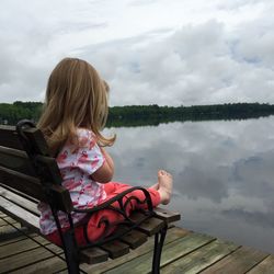 Woman sitting on bench by lake