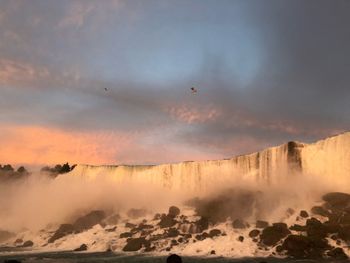 Scenic view of waterfall against sky during sunset