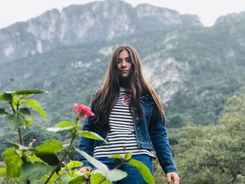 Portrait of young woman standing against mountain