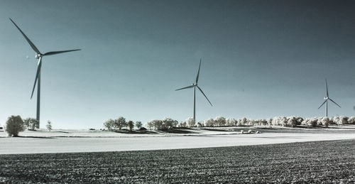 Wind turbines on field against clear sky