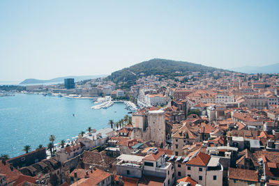 High angle view of townscape by sea against clear sky