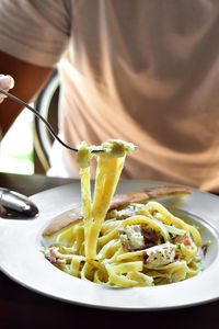 Midsection of person having pasta in plate