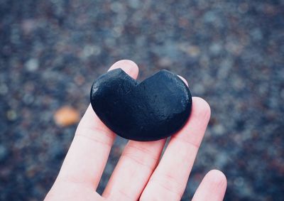 Close-up of hand holding heart shape stone