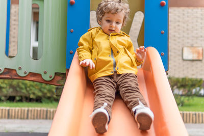 Full length of boy sliding on slide at park