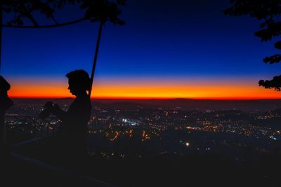 Silhouette man and cityscape against sky during sunset