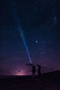 Silhouette people standing against star field at night