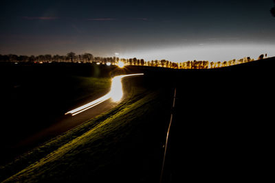 Light trails on road against sky at night