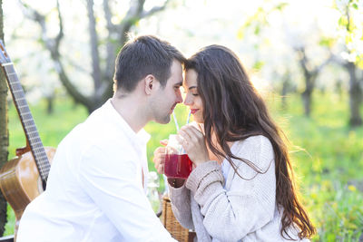 Side view of couple drinking against trees
