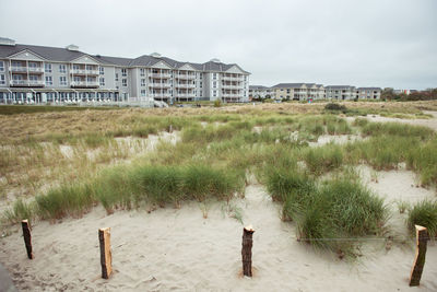 Residential district by grassy field against sky