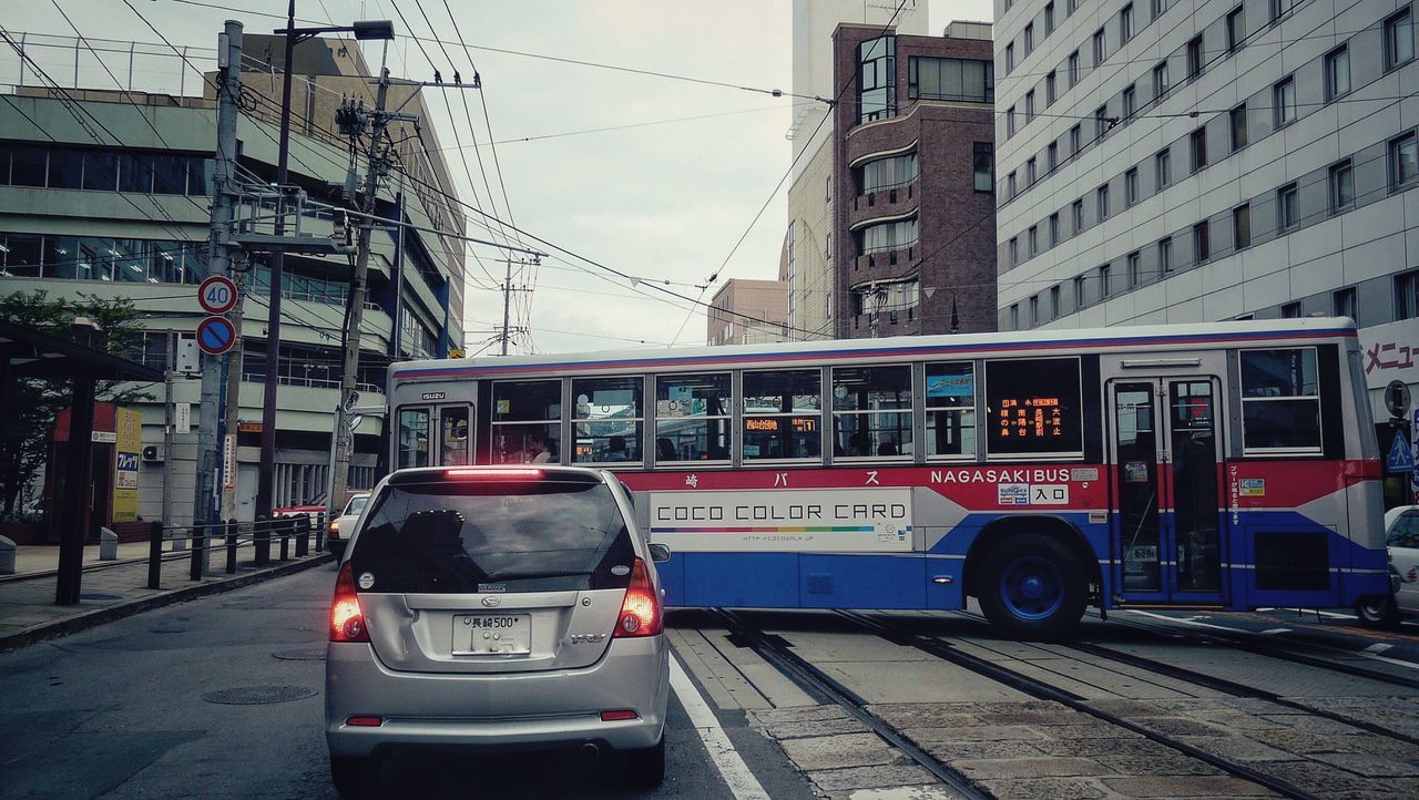 transportation, building exterior, architecture, built structure, railroad track, mode of transport, city, public transportation, land vehicle, rail transportation, car, street, power line, city life, railroad station, incidental people, railroad station platform, travel, outdoors, day