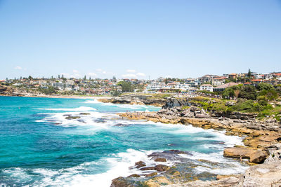 Scenic view of sea and buildings against clear blue sky