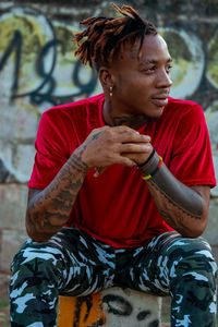 Young man looking away while sitting outdoors