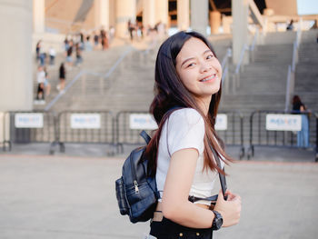 Portrait of young woman standing against building