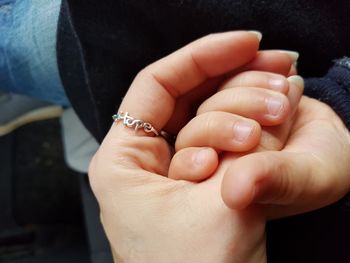 Close-up of mother holding son hand