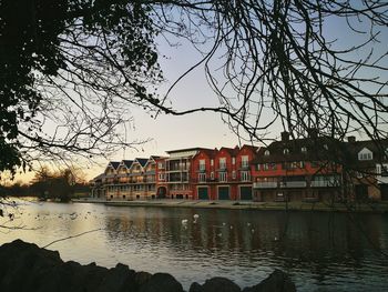 Canal by city against sky at sunset