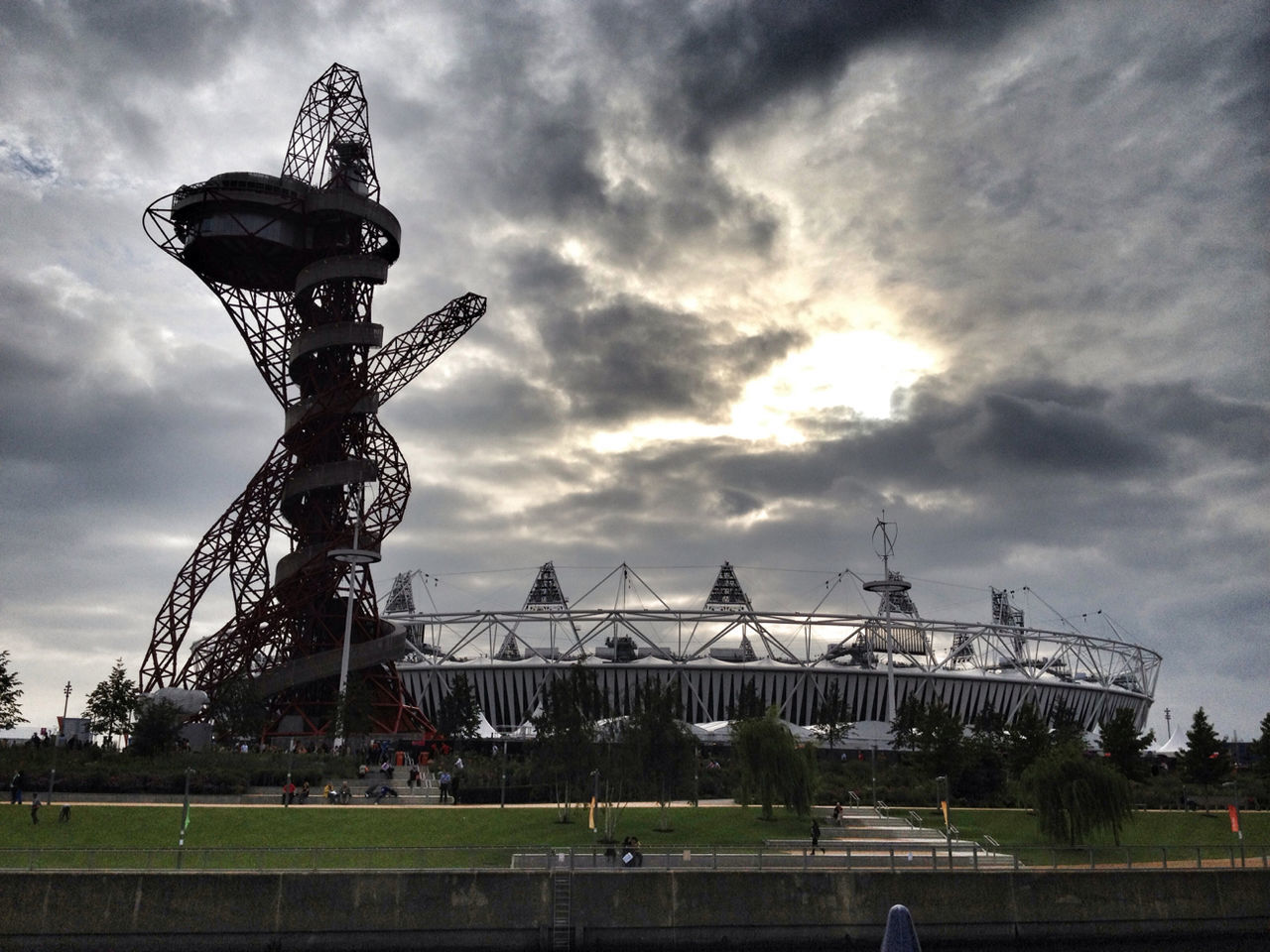 cloud - sky, sky, cloudy, transportation, mode of transport, land vehicle, weather, overcast, cloud, field, grass, architecture, built structure, storm cloud, dramatic sky, landscape, building exterior, dusk, amusement park, sunset