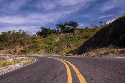 Surface level of road by trees against sky