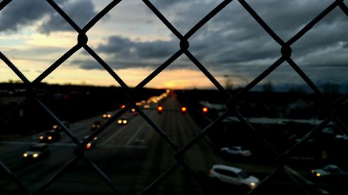 Close-up of chainlink fence against sky during sunset