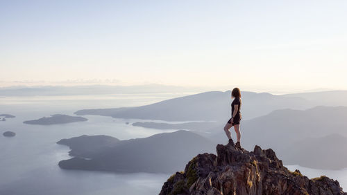 Man standing on rock against sky