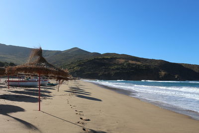 Scenic view of beach against clear blue sky