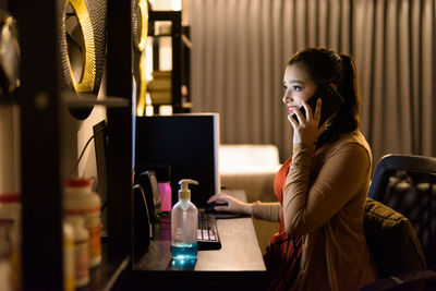 Young woman using phone while sitting on table