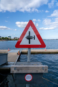 Warning sign by sea against sky