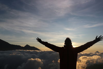 Rear view of woman standing against sky during sunset