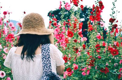 Rear view of woman with pink flowers against plants