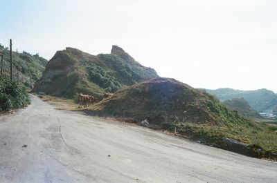 Road by mountains against clear sky