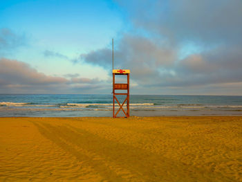 Lifeguard hut on beach against sky