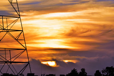 Low angle view of silhouette electricity pylon against sky during sunset