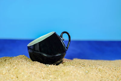 Close-up of sunglasses on beach against clear blue sky