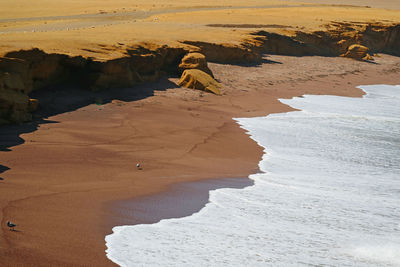 The red beach or playa roja with pure white wave foam from the pacific ocean, paracas peru