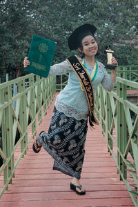 Portrait of smiling woman standing on footbridge