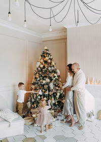 A family with children celebrate give gift boxes decorate a christmas tree in the interior the house