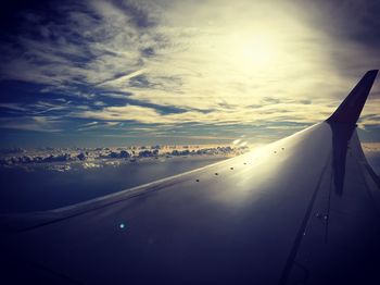 Cropped image of airplane flying over sea against sky