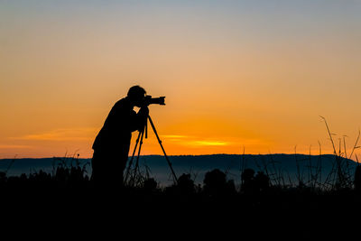 Silhouette of photographer against sky during sunset