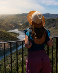 Rear view of woman standing by railing against mountain