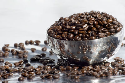 Close-up of roasted coffee beans in bowl on table
